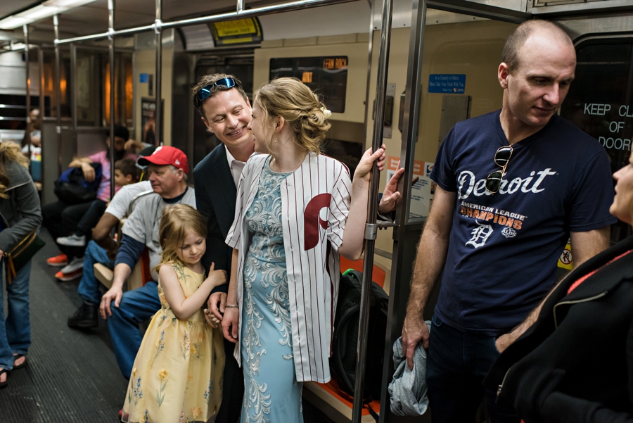 A wedding couple riding the subway to the way to their Phillies game reception.